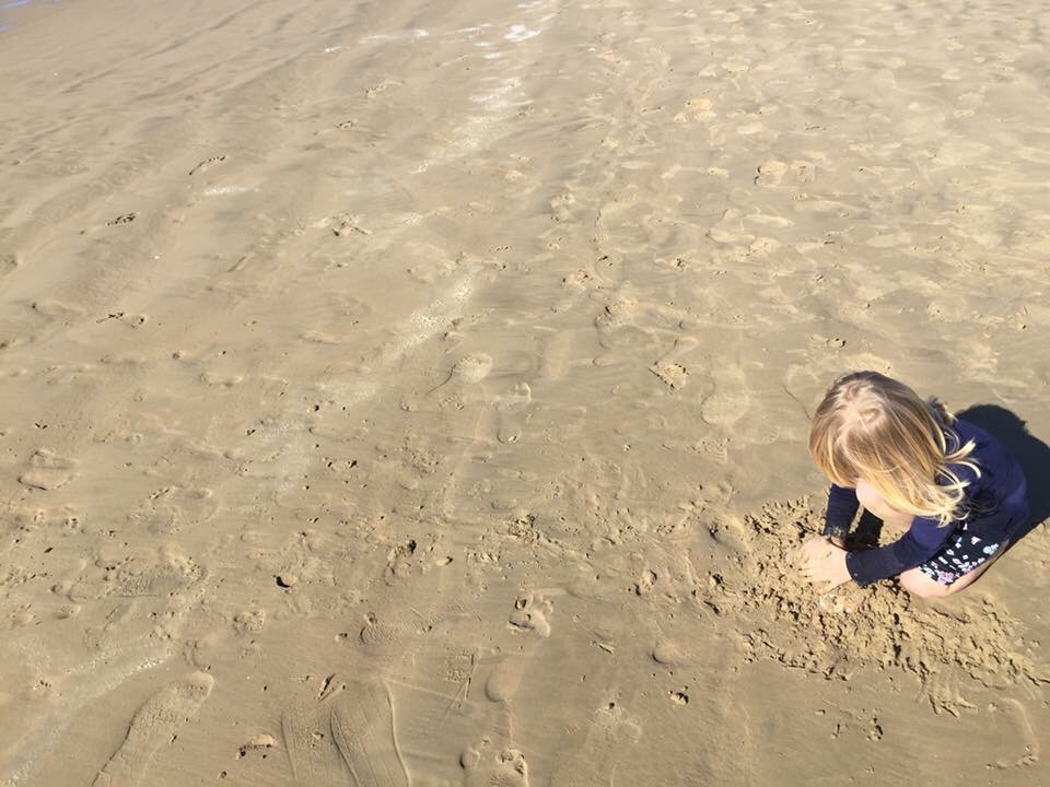 Toddler girl plays in sand in Pismo Beach California.
