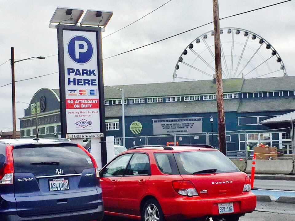 Family parks in lot across from the Seattle Aquarium with view of the Great Wheel.