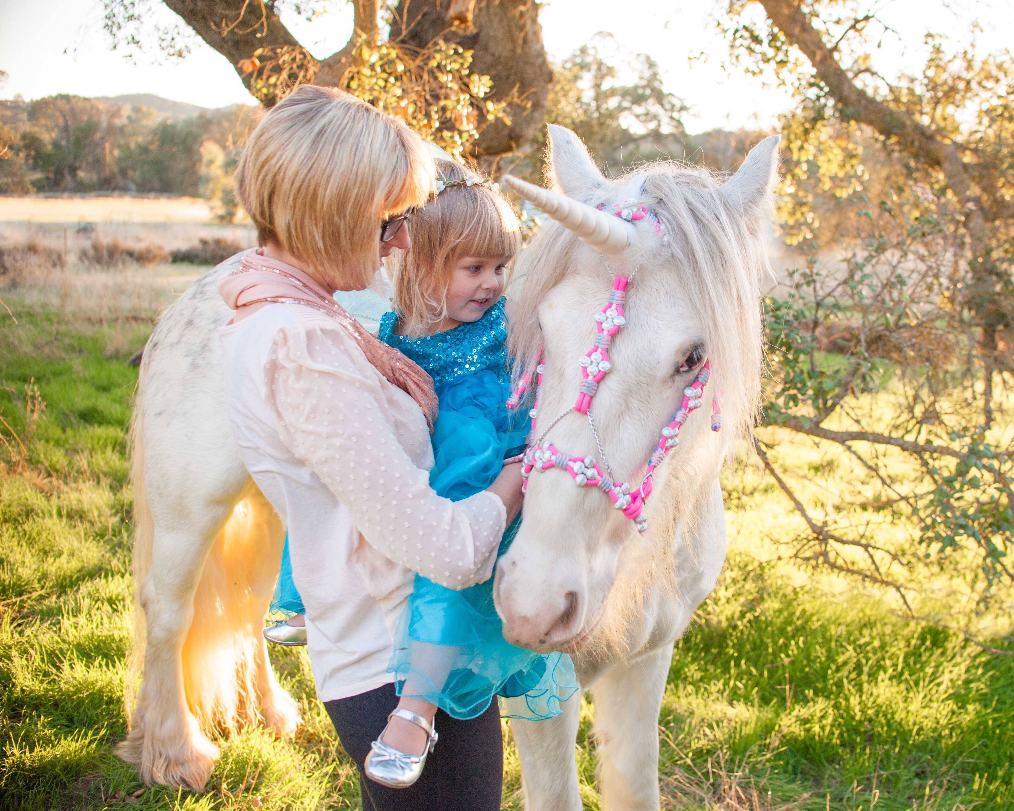 Mother and daughter stroke a unicorn's flowing white mane in Creston, California.