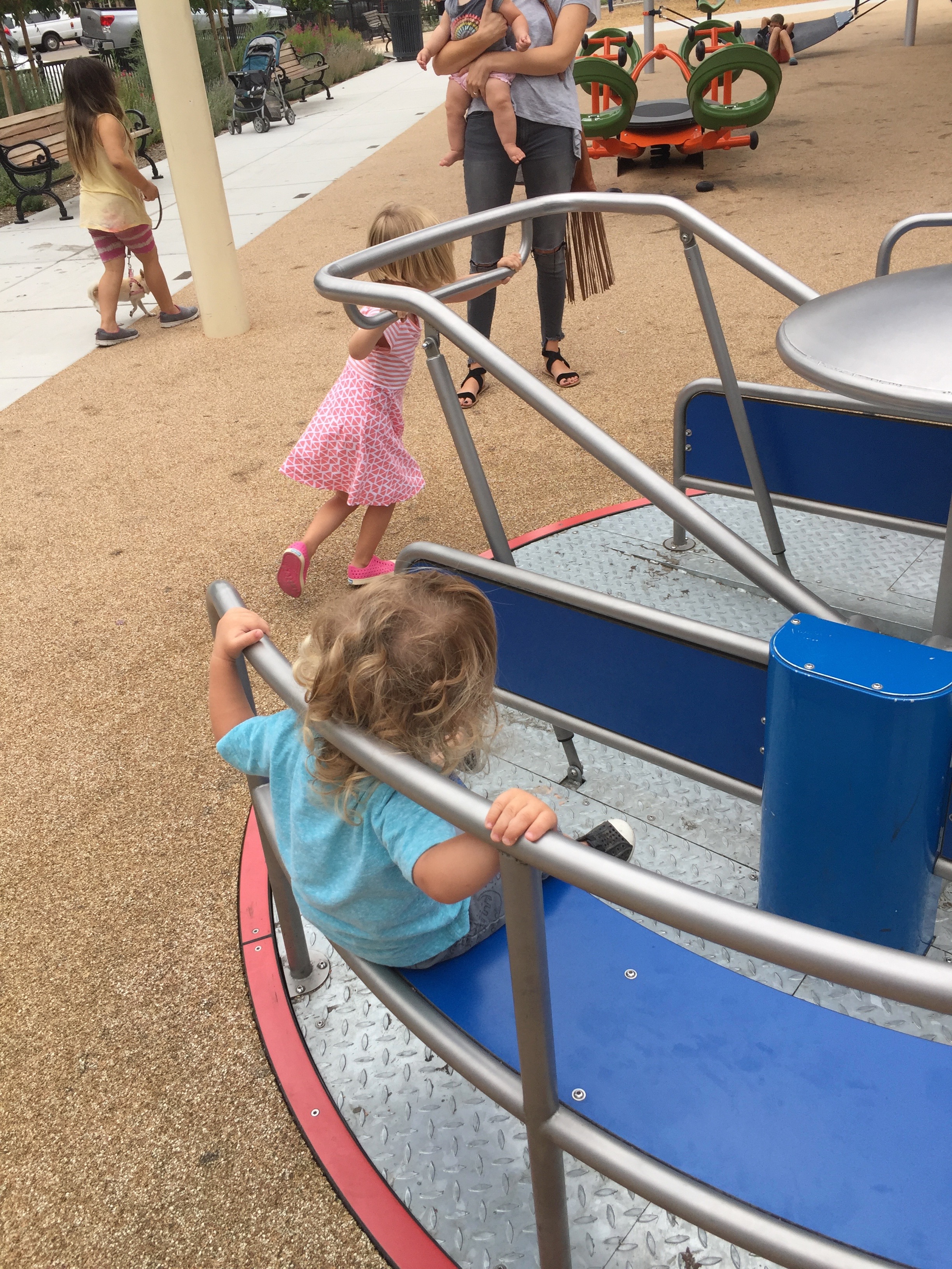 Kids pushing the new and modern merry-go-round at the Paso Robles Downtown City Park Playground