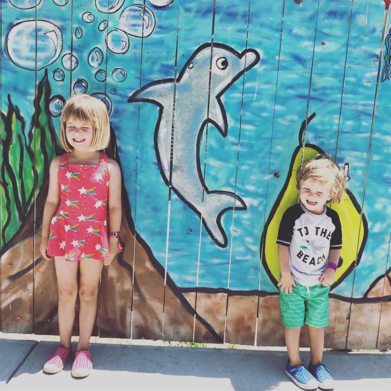 Two kids in front of wall mural with a painted dolphin