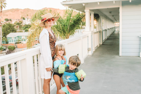 Mom posing in swimsuit and hat with kids at beach hotel