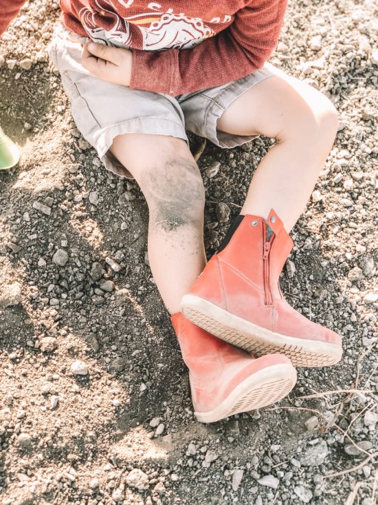 closeup in boy in dirt with Bobux Paddington Red Boot