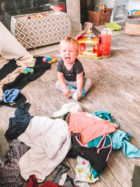 Baby crying with laundry on floor