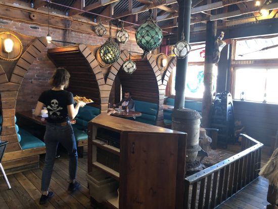 Nautical eatery interior with wood plank booths and fish nets