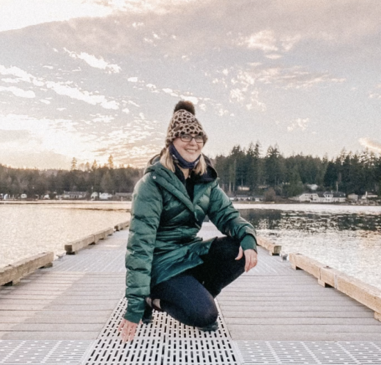 woman kneeling on pier under a beautiful sky