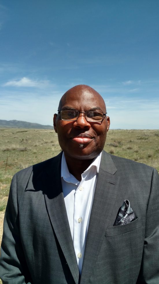 Image of a man standing in a suit in a field