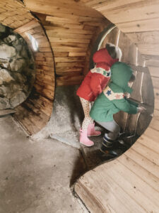 boy and girl peeking out a round wooden door