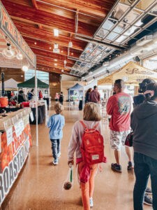 two kids walking around booth vendors in wooden building