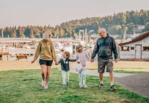 family on grass at harbor with boats