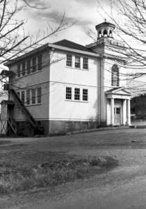 black and white photograph of old school building with tower and fire escapes.