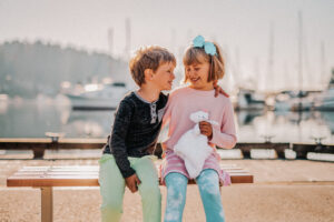 brother and sister sitting on bench as kids laughing