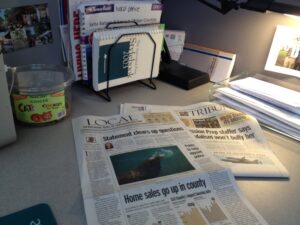 printed newspaper on a work desk with a lamp overhead