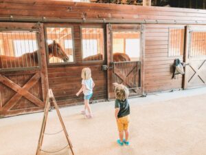 two little kids walking through a brown stable