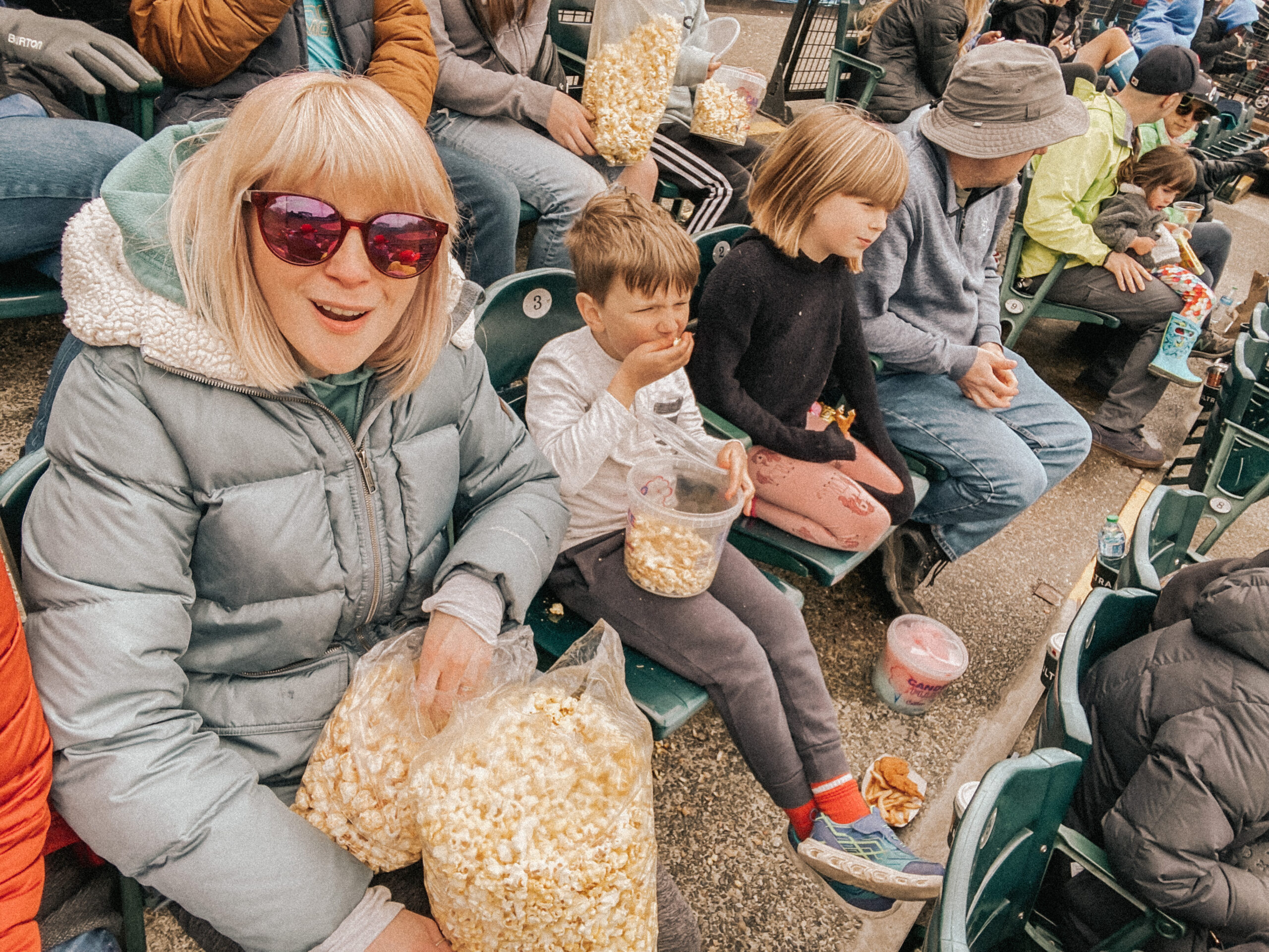 woman in blue coat with two bags of popcorn